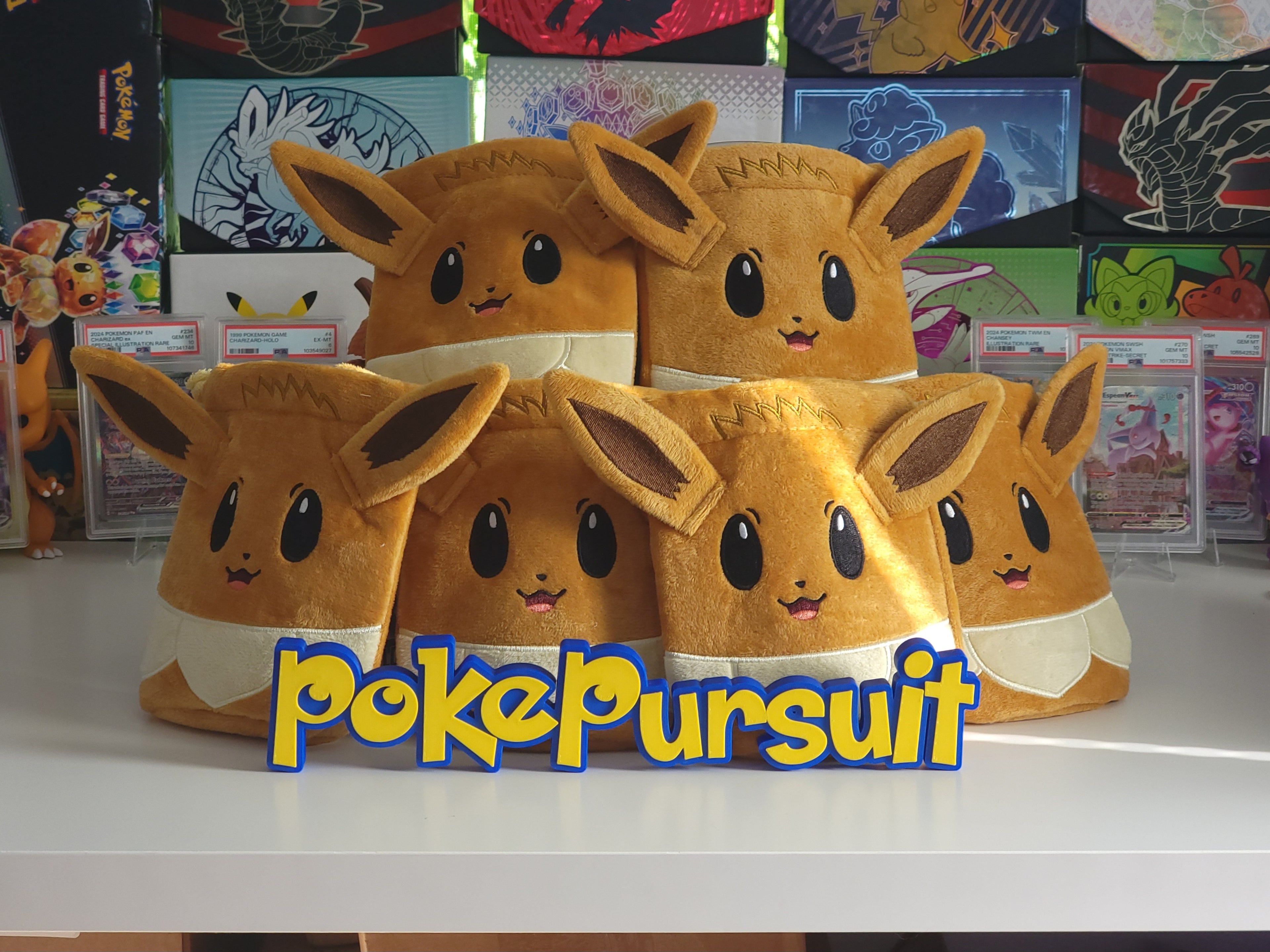 Plush toys resembling Eevee from Pokémon with 'pokePursuit' branding on a table.